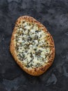 Gorgonzola, pear, honey, sesame pizza on a dark background, top view