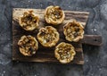 Gorgonzola, pears, honey, walnuts mini quiche on a wooden chopping board, top view on a dark background. Delicious appetizer,