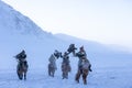 Golden eagle during the winter Mongolia local men riding on horses around the mountains covered with snow Royalty Free Stock Photo