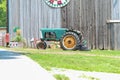 A tractor next to a barn and a social distancing sign