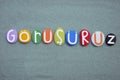 Gorusuruz, turkish word meaning, see you later, composed with multi colored stone letters over green sand