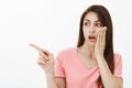 Gosh, just look what she wear. Portrait of shocked european female in pink t-shirt, holding palm on cheek and dropping