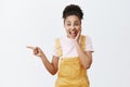 Gosh, what great news. Portrait of surprised good-looking amazed female in yellow stylish dungarees, holding palm on