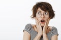 Gosh what happening look. Portrait of amazed and surprised cute female student in round glasses and striped t-shirt