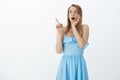 Gosh what it is. Portrait of stunned shocked and speechless attractive young blond girl in blue dress dropping jaw