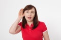 Gossip concept. Portrait of pretty middle aged woman with palm near her ear. Red blank shirt. Copy space and mock up Royalty Free Stock Photo