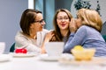 Gossips with best friends. Horizontal shot of two beautiful women whispering to their third friend`s ears while drinking Royalty Free Stock Photo