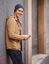 Got places to go and people to meet. a handsome young man sending a text message while leaning against a wall outside. Royalty Free Stock Photo