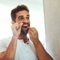 Got to look my best. a handsome young man flossing his teeth while looking at his reflection in the mirror at home. Royalty Free Stock Photo