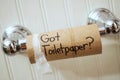 `Got Toilet Paper`, written in sharpie on cardboard toilet paper roll that is left hanging on the spool, on the wall