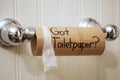 `Got Toilet Paper`, written in sharpie on cardboard toilet paper roll that is left hanging on the spool, on the wall