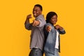 Gotcha. Joyful african man and woman pointing at camera with fingers