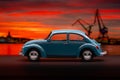 Blue Volkswagen Beetle toy car on sunset background.. Royalty Free Stock Photo