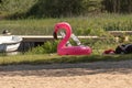 Large inflatable pink flamingo by a beach..