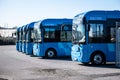 Row of new blue electric city buses at a depot..