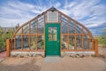 Gothic arch greenhouse with glass panel and green door below the stainless ventilation at Tucson, AZ Royalty Free Stock Photo