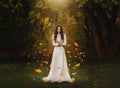 Gothic art photography fantasy woman creates magic. Bright divine light, autumn yellow leaves soar rotate fly in wind Royalty Free Stock Photo