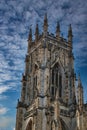 Gothic cathedral tower against a dramatic cloudy sky, showcasing intricate architectural details and spires, ideal for historical Royalty Free Stock Photo