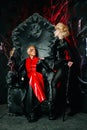 Gothic friends with dark make up in rock outfits on a huge scary throne ready for Halloween party