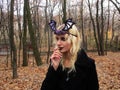 Gothic girl in a black crown with bat wings and a black coat in the forest Royalty Free Stock Photo