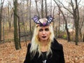 Gothic girl in a black crown with bat wings and a black coat in the forest Royalty Free Stock Photo