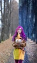 Gothic Girl with purple hair is standing with a burning glass in her hands in the alley in the autumn forest. Concept editing, pho