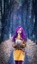 Gothic Girl with purple hair is standing with a burning glass in her hands in the alley in the autumn forest. Royalty Free Stock Photo