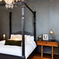 19 A Gothic-style bedroom with a mix of dark and textured finishes, a classic four-poster bed, and a mix of antique and modern d