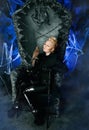 Gothic woman with bird on huge scary throne with blue spooky light ready for Halloween party