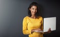 Gotta be web savvy in todays world. Studio portrait of an attractive young woman using a laptop against a gray Royalty Free Stock Photo