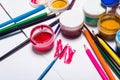 Gouache paint, brushes, and colored pencils on a light background Royalty Free Stock Photo