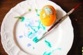 A gouache-painted yellow Easter egg on a white plate with a tassel Royalty Free Stock Photo