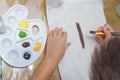 Gouache and paper for painting and child drawing. Kid hands painting at the table with art supplies, top view . Top view child's