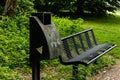 Gouda, South Holland/The Netherlands - May 19 2018: Dark green bench and bin along a hinking path in the city park