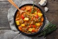 Goulash, beef stew or bogrash soup with meat, vegetables and spices in cast iron pan on wooden table.