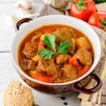 Goulash in ceramic bowl on white wooden background. Traditional hungarian soup. Royalty Free Stock Photo