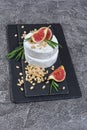 Gourmet appetizer of white brie cheese or camembert with fresh figs, nuts, honey and rosemary spice on black slate board Royalty Free Stock Photo