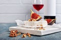 Gourmet appetizer of white brie cheese or camembert with fresh figs, nuts and red wine on wooden cutting board Royalty Free Stock Photo