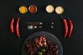 gourmet assorted meat on slate board, fork with knife, various sauces and chili peppers on black