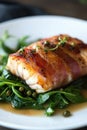 Gourmet bacon wrapped fish on spinach with fresh herbs and capers Royalty Free Stock Photo