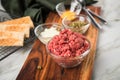 Gourmet beefsteak Tatar with lean raw beef filet, capers, egg yolk, onions, toast bread on wooden board and light marble