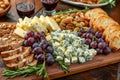 Gourmet Cheese Platter with a Variety of Cheeses, Nuts, Grapes, Artisan Bread, and Red Wine on Wooden Table for Elegant Party Royalty Free Stock Photo