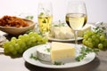 Gourmet Cheese Selection Plate with Fresh Grapes, White Wine Glasses, and Bottle on White Background