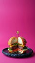 Gourmet cheeseburger halves on black plate against vibrant pink background Royalty Free Stock Photo
