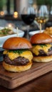 Gourmet cheeseburger sliders on a wooden board alongside wine glasses at a restaurant perfect for dining out at an Royalty Free Stock Photo