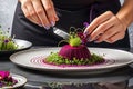 Gourmet Chef Plating an Intricate Dish: Arranging a Delicate Microgreen Salad Atop a Spiral of Ruby Elegance Royalty Free Stock Photo