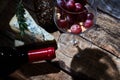 Gourmet composition of wineglass with grapes and walnuts on wood table with cheese and bottle of red wine