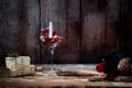 Gourmet composition of wineglass with grapes and walnuts on wood table with cheese and bottle of red wine. Copy space