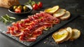 Gourmet Cured Meat Slices Served on Slate with Crusty Bread, Tomatoes, Olives, and Rosemary on a Dark Table Fine Dining Appetizer