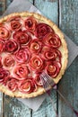 Gourmet dessert. Apple rose pie with cream filling served on baking paper with forks on blue wooden background Royalty Free Stock Photo